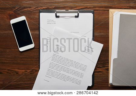 Top View Of Documets On Clipboard, Smartphone And Folder On Table