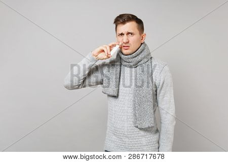 Abhorred Young Man In Gray Sweater, Scarf Holding Nasal Drops Near Nose Isolated On Grey Background 