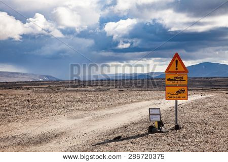 Deep ford and rough gravel road warning roadsign and Road F26 closed due to snow alert sign at ÃdÃ¡Ã°ahraun lava field in Highlands of Iceland, Scandinavia. Rainy cloud is seen in background