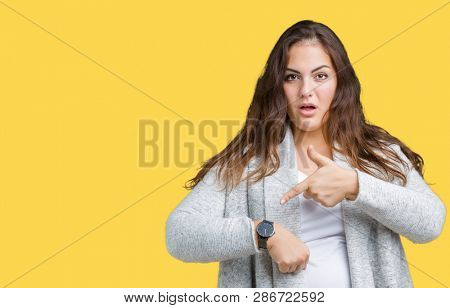 Beautiful plus size young woman wearing winter jacket over isolated background In hurry pointing to watch time, impatience, upset and angry for deadline delay