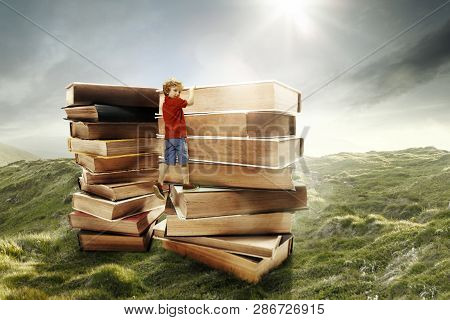 Little Boy Climbing On The Tower Made Of Big Books. Childhood Dreams, Reading And Education Concept.