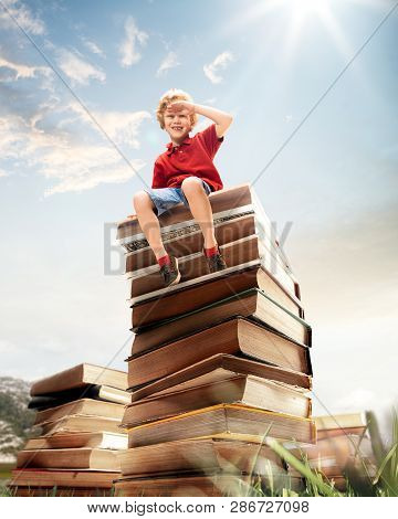 Little Boy Sitting On The Tower Made Of Big Books. Childhood Dreams, Reading And Education Concept. 