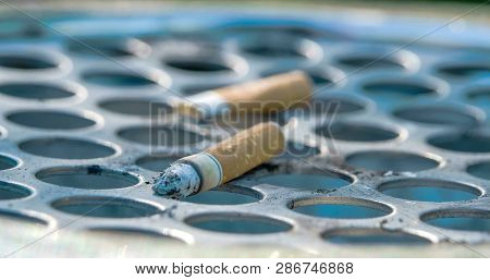 Close Up View Of The Cigarette Butt On The Bin. The Cigarette Did Not Get Inside The Cigarette Bin