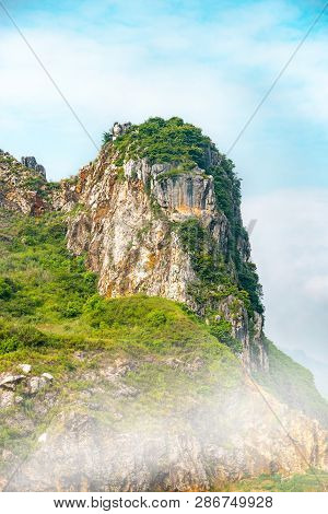 White Rock Mountain Tower With Smoke/fog/mist And Cloudy Blue Sky. Masigit Limestone Mountain In Wes