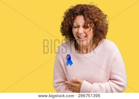 Middle ager senior woman wearing changeable blue color ribbon awareness over isolated background Smiling and laughing hard out loud because funny crazy joke. Happy expression.