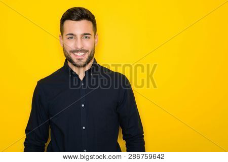 Young handsome man possing and modeling over yellow isolated background