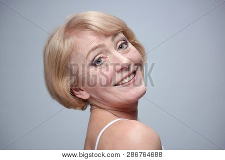 beauty portrait of mature caucasian woman blond face skin teeth thoothy smile isolated on blue background