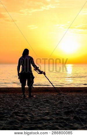 Man Silhouette With Metal Detector On The Beach In Sun Set