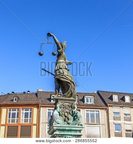 Lady Justice Standing At The Fountain Under Blue Sky In Frankfurt As A Symbol Of Justice