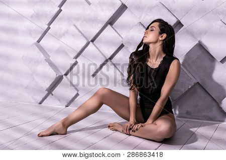 Bewitching Good-appealing Slim Woman Sitting Lightsome Amid Studio Shooting