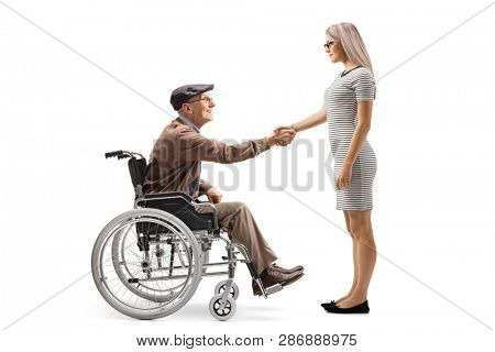 Full length shot of a happy senior man in a wheelchair shaking hands with a young woman isolated on white background