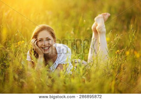 Happy Girl Lies In The Grass In The Field