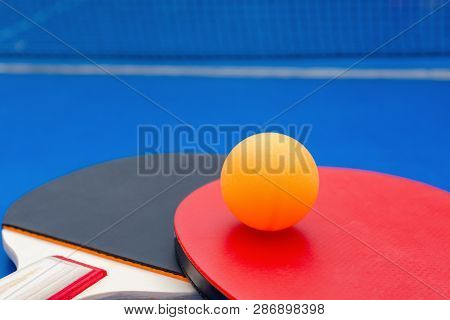 Pingpong Rackets And Ball And Net On A Blue Pingpong Table