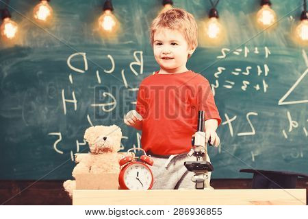 Child, Pupil On Calm Face Near Microscope. Kid Boy Near Microscope In Classroom, Chalkboard On Backg
