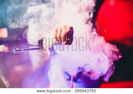 Man Smokes A Hookah And Breathes A Large Cloud Of Tobacco Smoke
