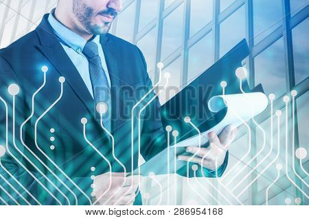 Unrecognizable Bearded Businessman Standing With Clipboard Over Skyscraper Background With Circuits.