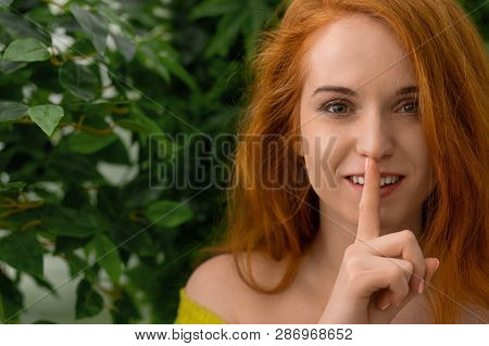 Keep Silence. Young Redhead Caucasian Woman Holding Index Finger At Lips, Asking Toor Not Tell Anyon