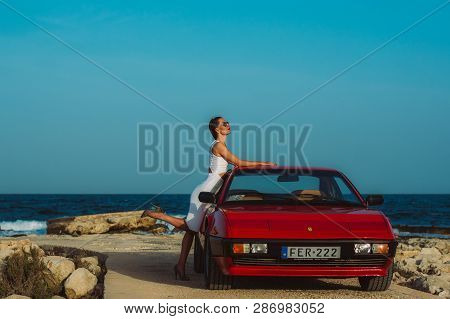 Young Beautiful Girl In Sunglasses Posing Near The Red Ferrari