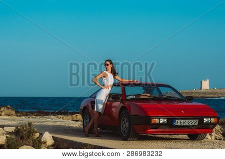 Young Beautiful Girl In Sunglasses Posing Near The Red Ferrari