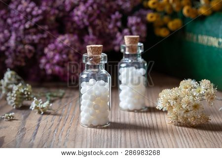 Bottles Of Homeopathic Globules With Dried Herbs And A Materia Medica, I.e. A Book Of Remedies And T