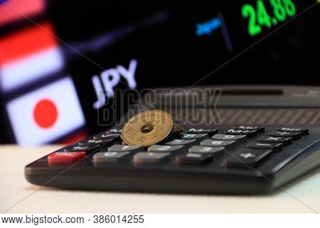 Japanese Five Yen Coins (jpy) On White Floor With Black Calculator And Digital Board Of Currency Exc