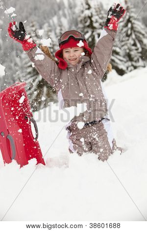Jong meisje spelen In sneeuw met Sledge op skivakantie In Bergen