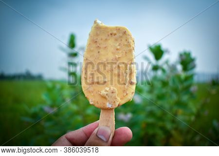 Man's Hands Holding Ice Cream In A Green Background