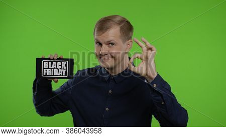 Happy Cheerful Blonde Man Holding Black Friday Inscription And Showing Ok Sign. Guy Rejoicing With G