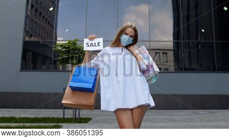 Young Stylish Model Girl In Protective Mask With Shopping Bags Showing Sale Word Inscription Text, L