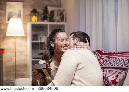 Young Woman Gives A Big Hug To Her Husband On Christmas Day After He Gives Her A Gift.