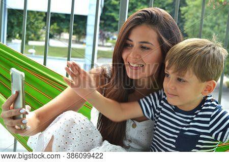 Mother and son sharing on hamaca using cell phone.Stay at home cell phone chat.