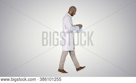 Arabic Doctor Walking And Putting Medical Cap On On Gradient Bac
