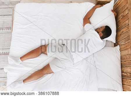 Unrecognizable Black Guy Sleeping Lying On Stomach In Bed At Home. African Man Resting And Relaxing 