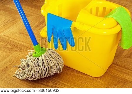 Floor Cleaning Mop And Gloves On A Yellow Bucket. The Cleaner Will Create Hygiene On The House