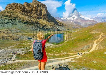 Hiker Woman Backpacker Pointed Mount Matterhorn Or Monte Cervino Or Mont Cervin, And Swiss Alps And 