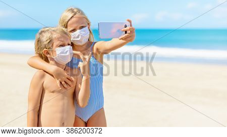Funny Kids Taking Selfie Photo By Smartphone On Tropical Sea Beach. New Rules To Wear Cloth Face Cov