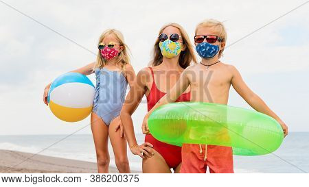 Funny Children In Sunglasses, Inflatable Toys On Tropical Sea Beach. New Rules To Wear Cloth Face Co