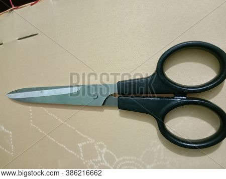 Silver And Black Colored Scissors Closeup On Golden Background