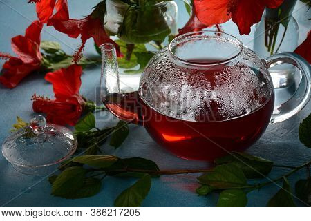 Hibiscus Tea In A Glass Transparent Teapot, And Blossom Flower