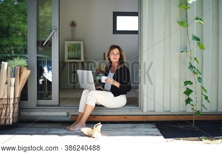 Mature Woman Working In Home Office In Container House In Backyard.