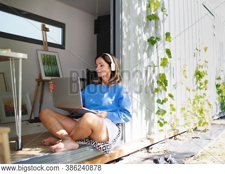 Mature Woman Working In Home Office In Container House In Backyard.