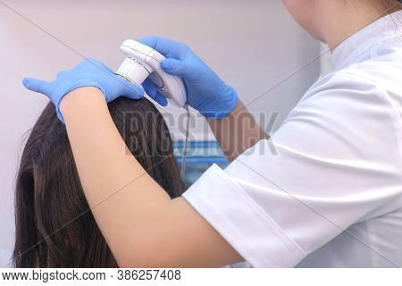 Doctor Trichologist Examines Woman Patients Hairs Using Trichoscope In Clinic, Closeup Hand View. Ru