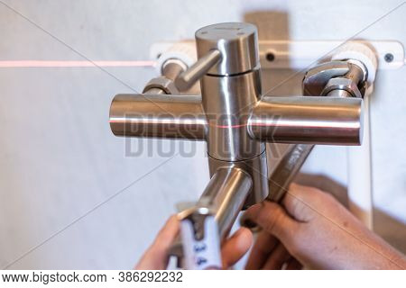 Plumber Assembles An Iron Faucet For Tap Water Using A Key And A Laser Level. Plumbing Installation 