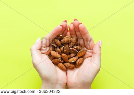 A Hand Holding Almonds On A Light Green Background