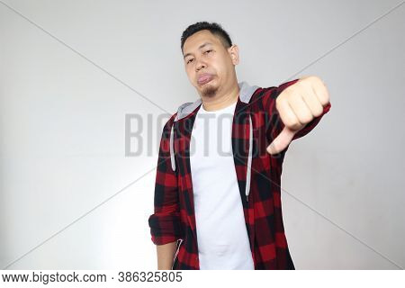 Portrait Young Asian Man Wearing Casual Shirt Shows Upset Expression With Thumbs Down, Over White Ba