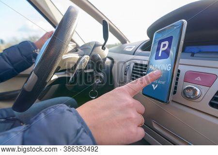 Woman using smartphone app to pay for parking in the paid parking zone in a city