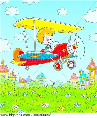 Little Cheerful Boy Piloting His Small Toy Plane Among White Clouds In Blue Summer Sky Over A Green 