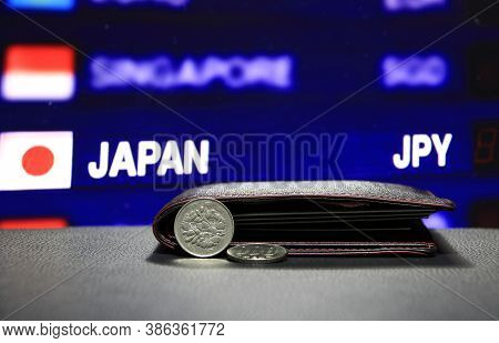 Japanese One Hundred Yen Coins On Obverse (jpy) And One Coin Laying On Black Floor With Black Wallet