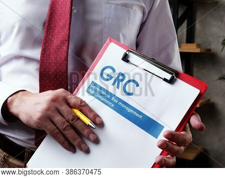 Businessman With Grc Governance Risk Management And Compliance Documents.