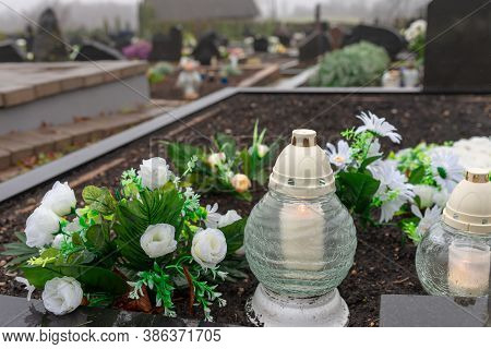 A Candle And Fake White Roses At A Cemetery.first November Concept.at Morning